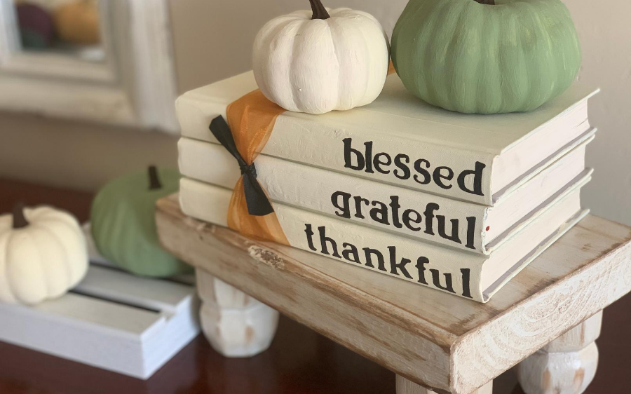 White books stacked with black writing and pumpkins