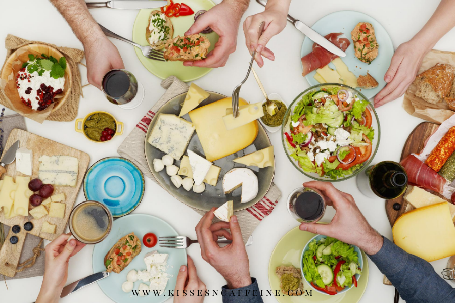 Table with lots of food and hands grabbing for that food