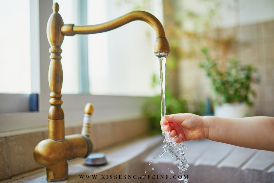 Faucet with running water and child's hand under the flow