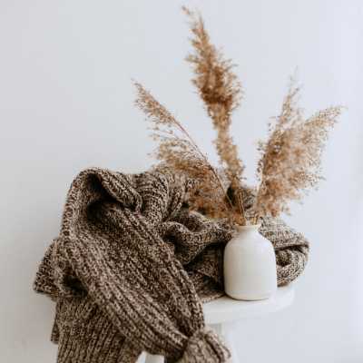 Pampas leaf in a white jar and a sweater on a table