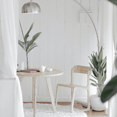 Table and chair with green plants and a silver lamp