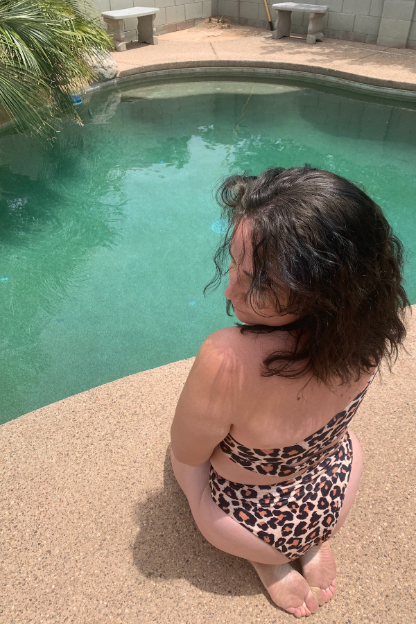 Sitting near pool in leopard bathing suit