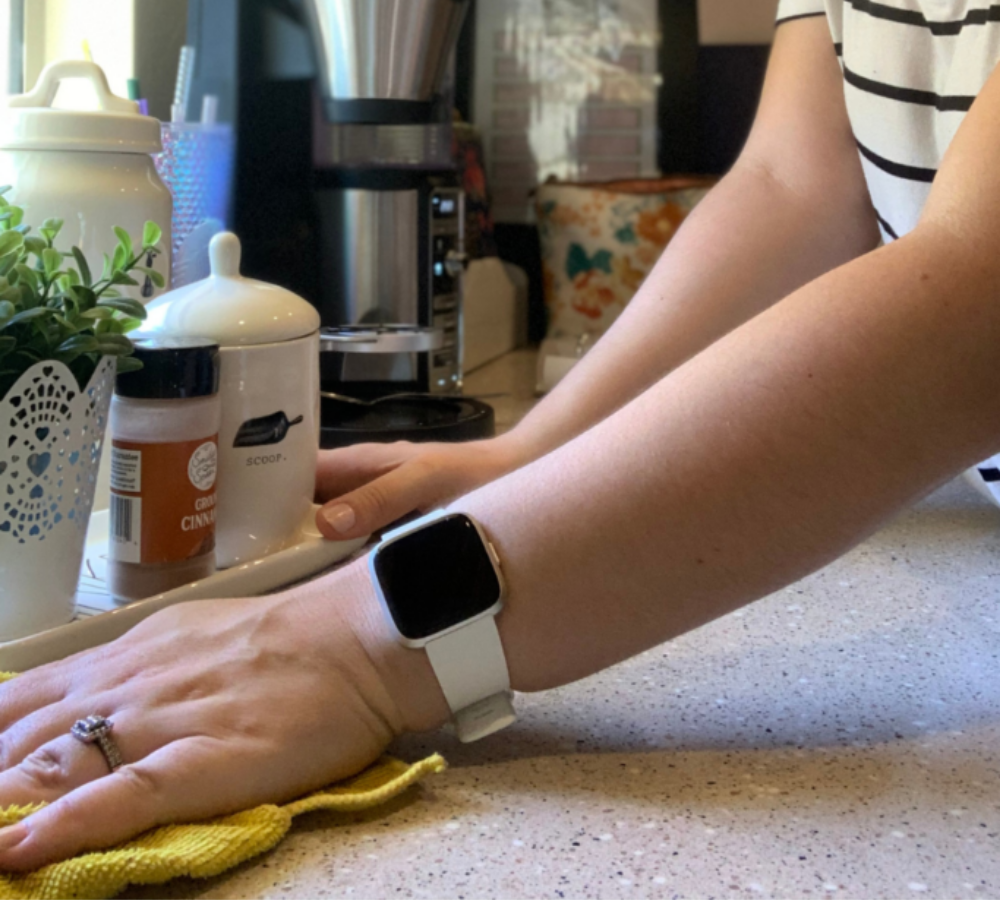 Hands wiping a counter with a yellow rag