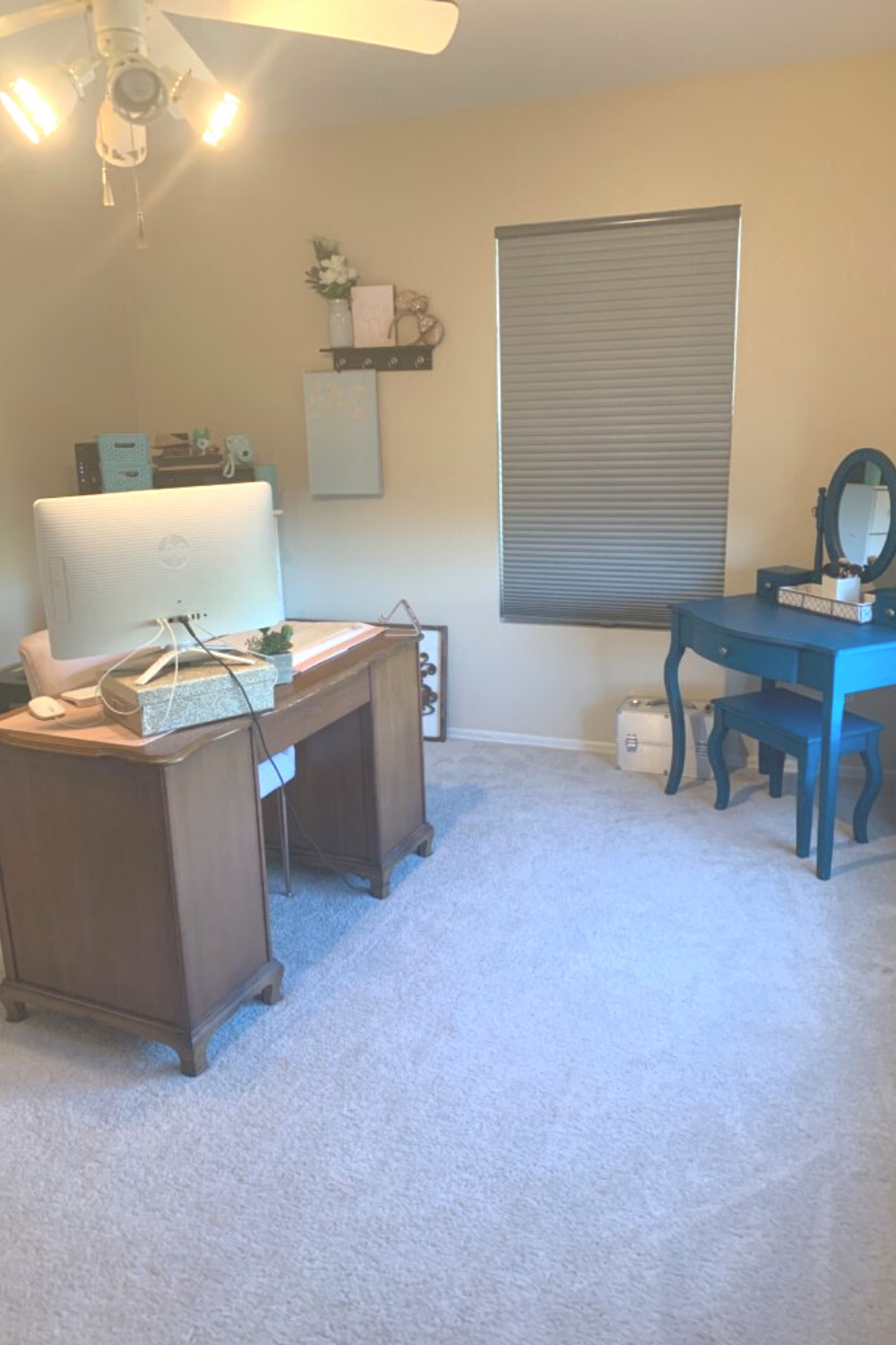 A teal table across from a brown desk with a computer sitting on top