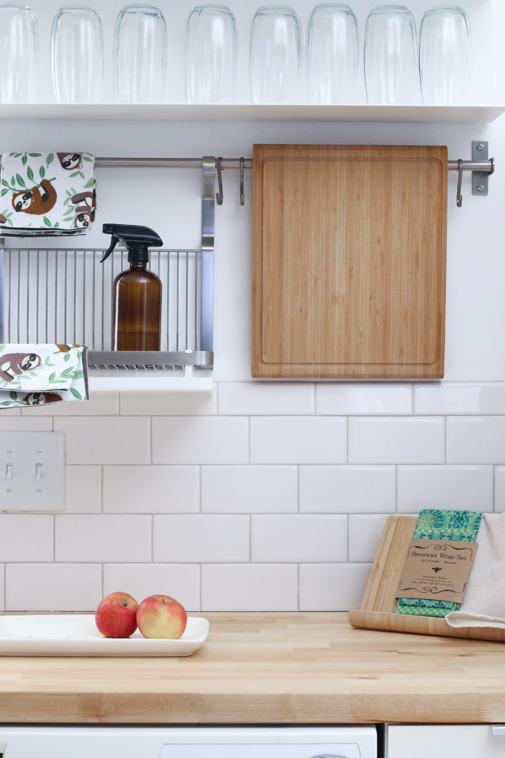 Kitchen counters with a cookbook, apples, and a drying rack hanging on the wall