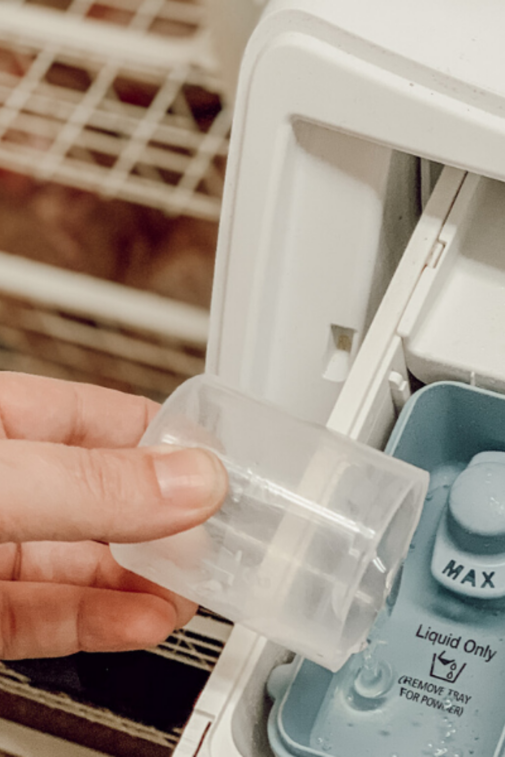 A hand pouring soap into the tray for washing machine product