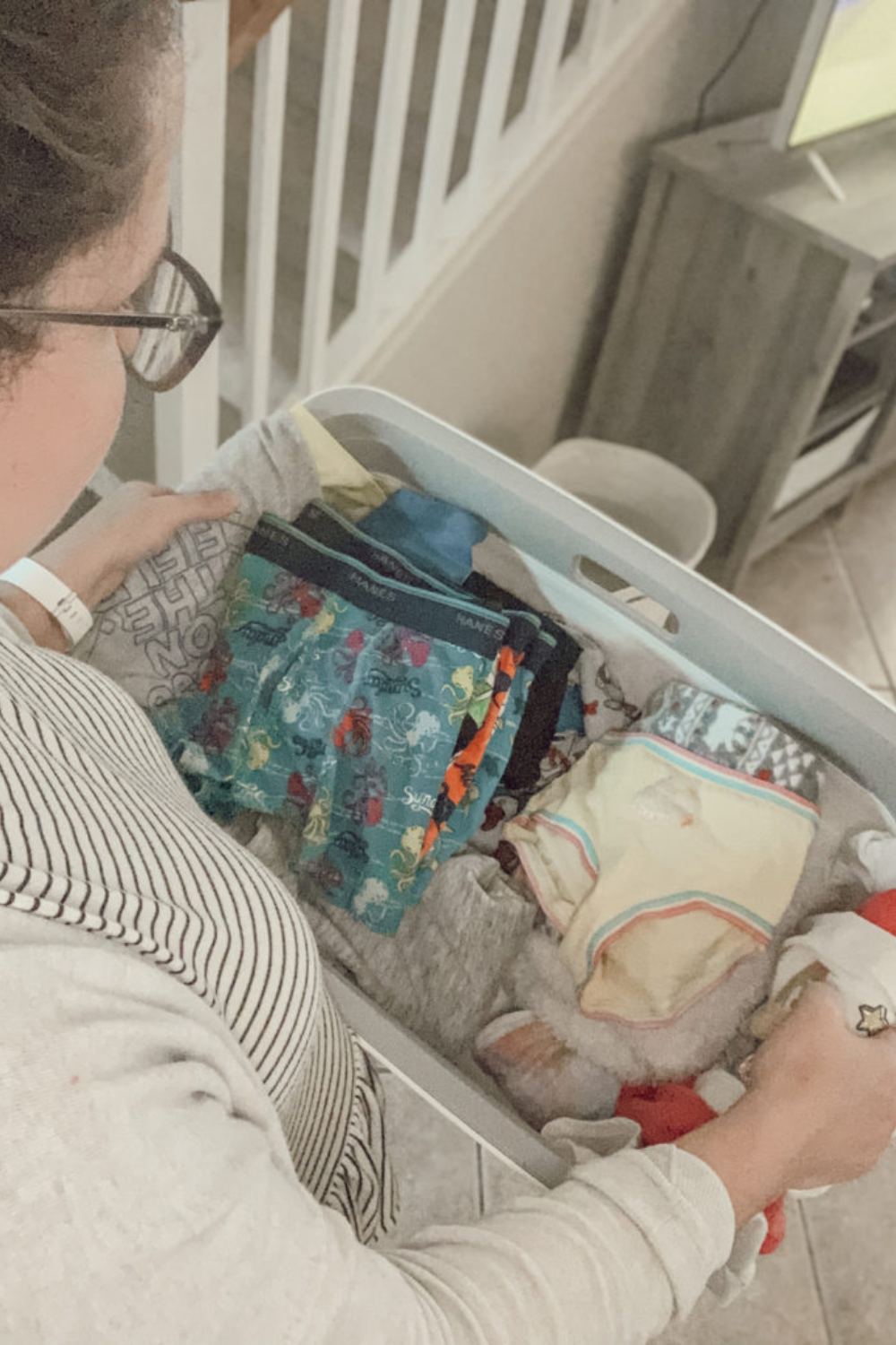 Carrying kids clothes in a laundry basket wearing a striped shirt