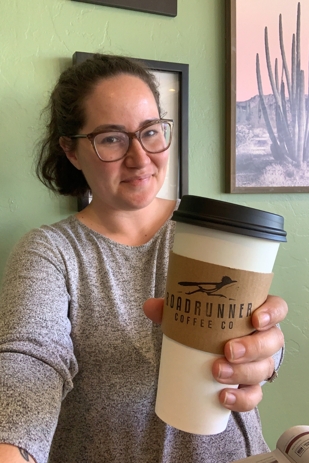 Me holding a cup of coffee that says Roadrunner Coffee Co.