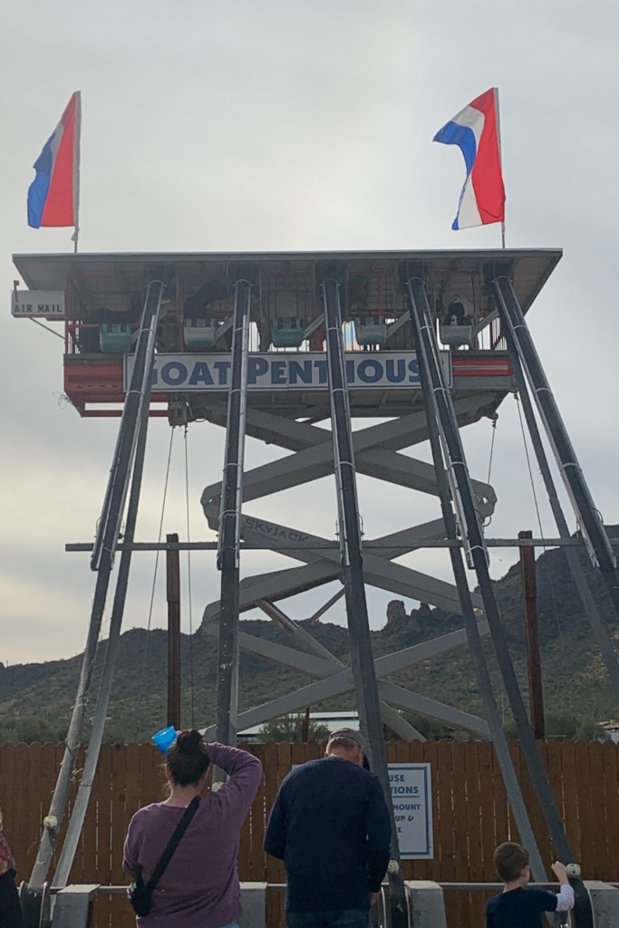 A large twoer with red and blue flags with a pulley system to feed goats up at the top