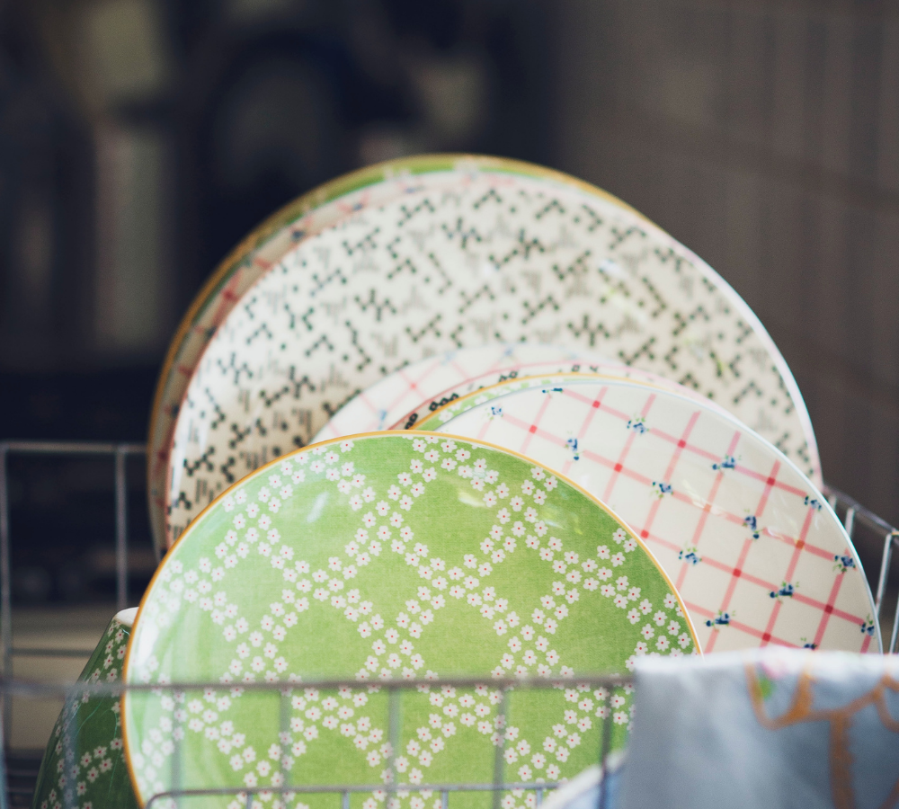 Green and white plates lined up in a silver drying rack