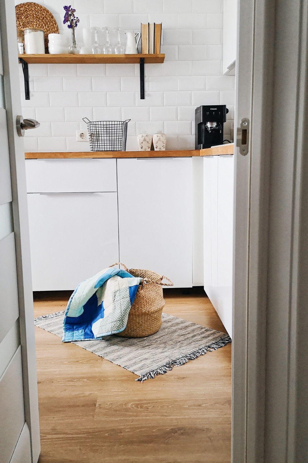 White laundry room with white cabinets, brown counters and a basket on the ground w a towel hanging off of it