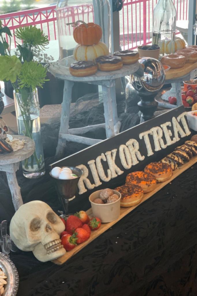 Table covered in donuts, Halloween decor and fruit