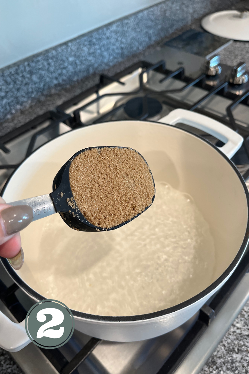 Hand pouring brown sugar into a white pot