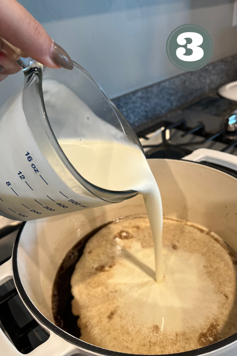 Hand pouring cream into a white pot on the stove