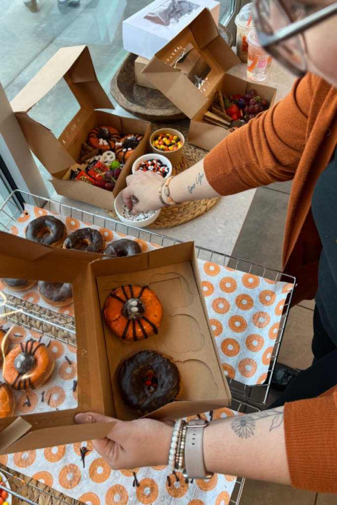 Putting together a box of donuts, wearing an orange sweater